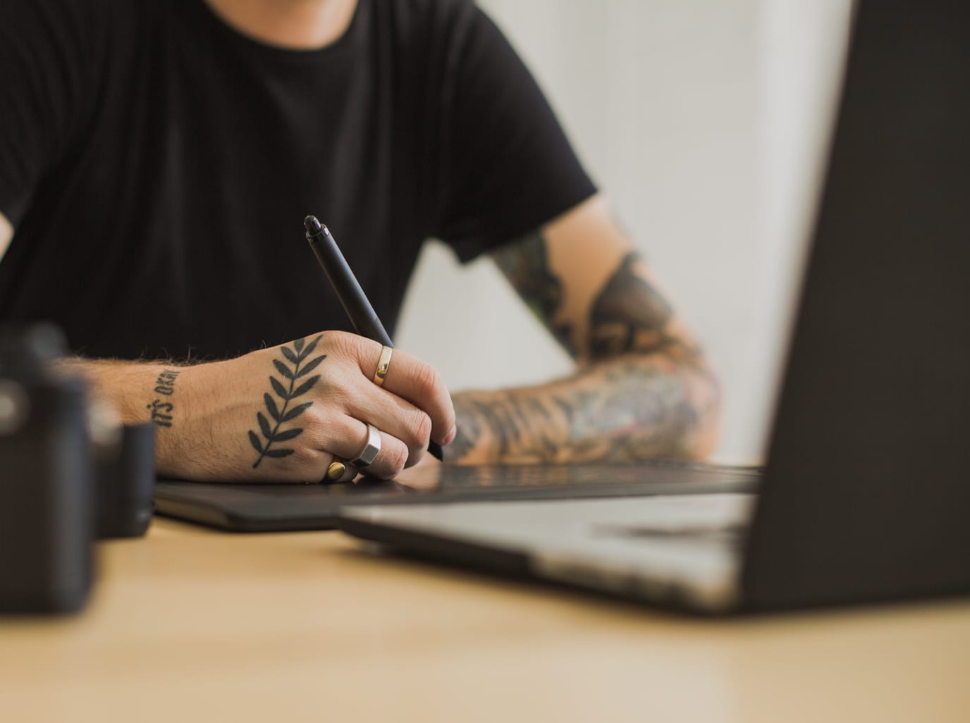 A man with tattoos takes notes in front of his computer before beginning work at website design and development company