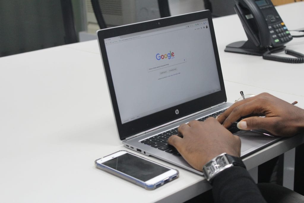 Man typing on laptop with Google Search open in browser